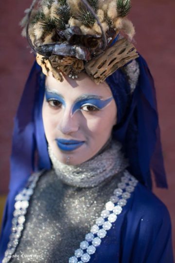 Houda in costume with blue eyeshadow and lipstick and wearing a blue and silver costume